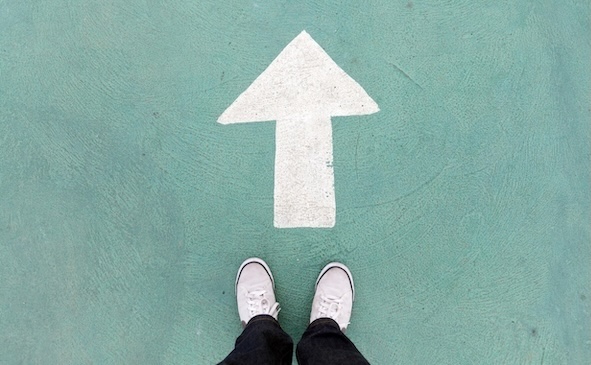 Auf dem Betonboden stehende Schuhe und weißes Wegweiser, um weiter zu gehen