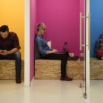 KI und Ethik. Menschen in Einzelkabinen an verschiedenen Devices am Arbeiten. Schattenseiten der Künstlichen Intelligenz