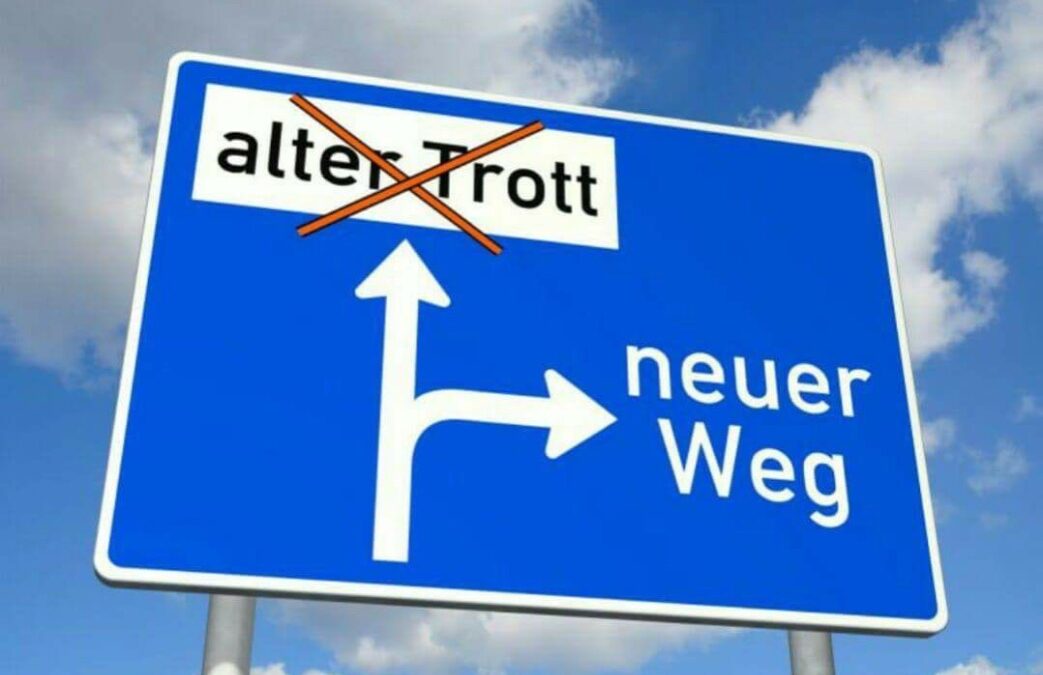 blaue Strassenanzeigetafel. Darauf steht ein Wegweiser mit Alter Trott geradeaus und ein Pfeil rechts ab Neuer Weg. Neuer Weg: Gewaltfreie Kommunikation und Wertschätzung